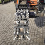 Frontalaufnahme eines hydraulischen Grabenfräskopfes an einem Bagger. Zu sehen sind zahlreiche Meißelzähne auf mehreren Walzen, die zum Fräsen von Boden und Asphalt eingesetzt werden.