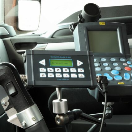 Nahaufnahme der Steuer- und Bedienelemente für Winterdienstfunktionen im LKW-Fahrerhaus, darunter ein Displaymodul, Tastatur und Joystick zur hydraulischen Steuerung.